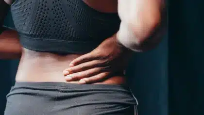 Femme tenant son abdomen, exprimant une gêne ou une douleur liée à une infection urinaire
