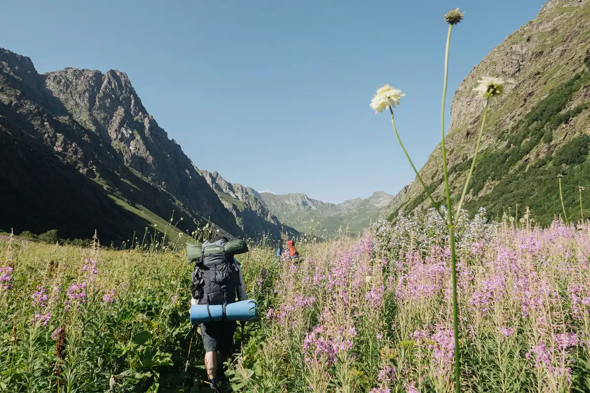 Randonneur avec sac &agrave; dos bien &eacute;quip&eacute; sur un sentier de montagne ensoleill&eacute;.
