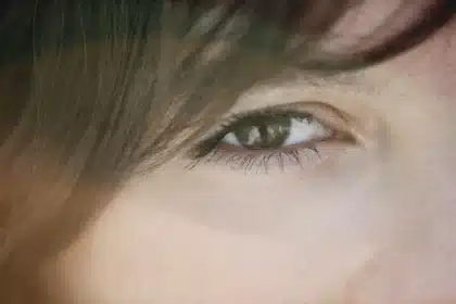 Femme de profil, main près des yeux, lumière douce symbolisant les changements hormonaux et visuels