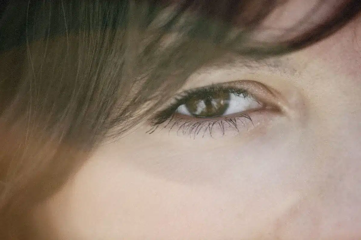 Femme de profil, main près des yeux, lumière douce symbolisant les changements hormonaux et visuels