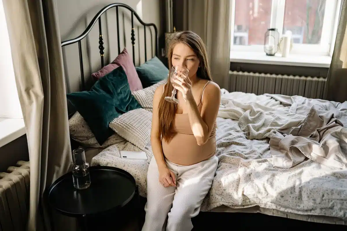 Femme enceinte au repos avec une bouteille d'eau pour rester hydratée