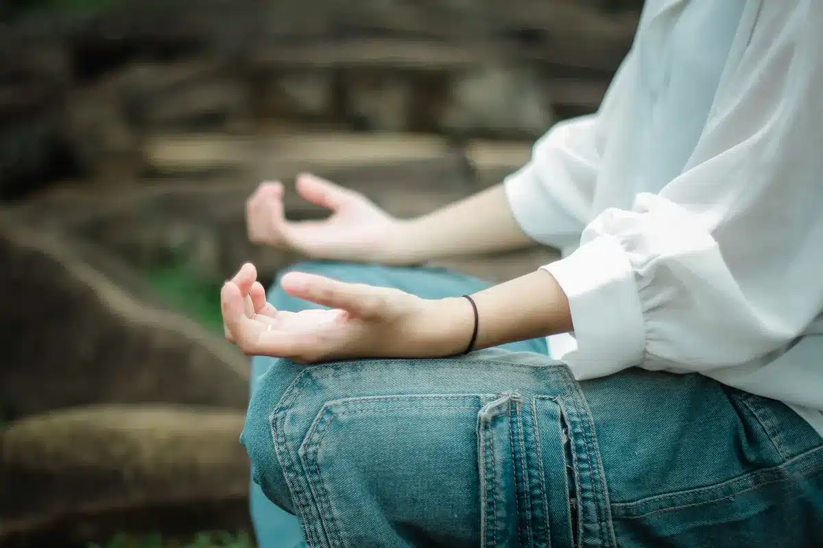 Personne détendue dans un environnement serein, représentant la réduction du stress par la méditation.