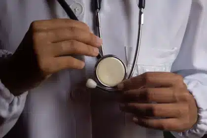 Patient en consultation médicale avec un médecin dans un cabinet, documents médicaux sur le bureau.