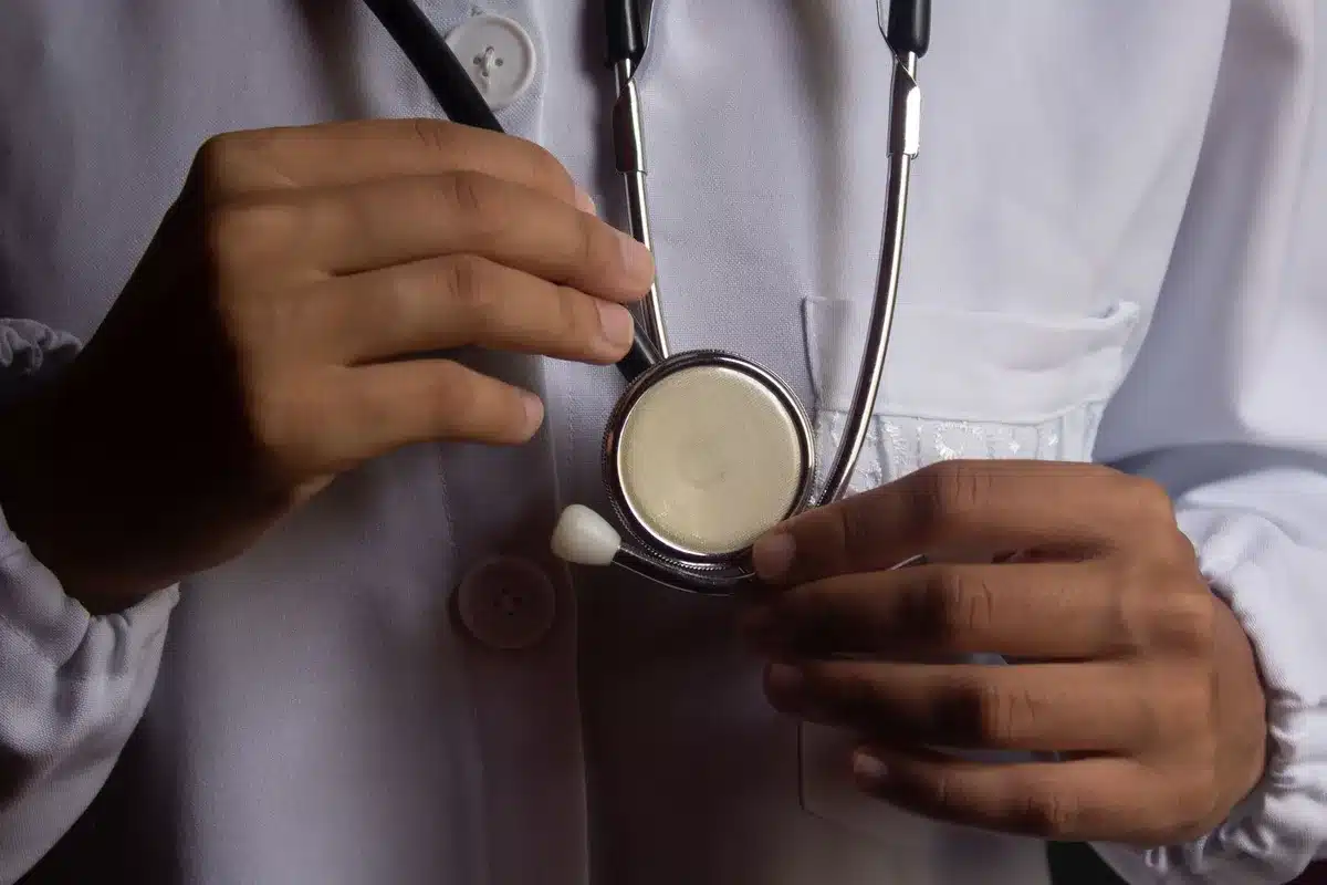 Patient en consultation médicale avec un médecin dans un cabinet, documents médicaux sur le bureau.