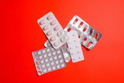 Main de femme tenant une plaquette de pilule contraceptive au-dessus d'un calendrier avec une date entourée