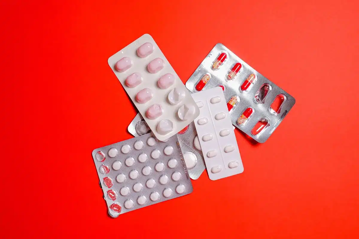 Main de femme tenant une plaquette de pilule contraceptive au-dessus d'un calendrier avec une date entourée