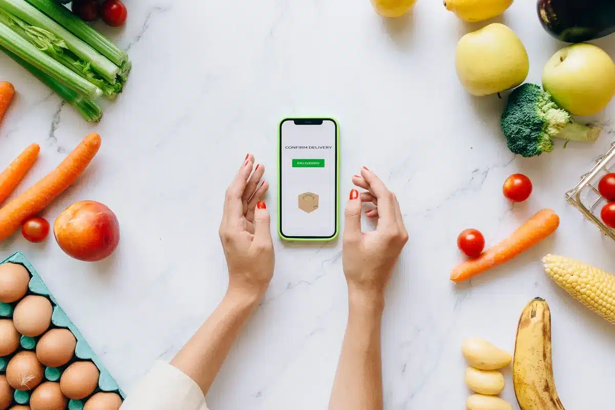 Écran de téléphone affichant des vidéos de tendances culinaires, entouré d'ingrédients frais sur une table