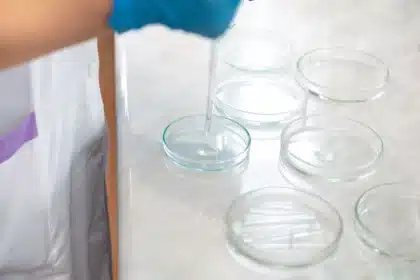 Mains de chercheur tenant un modèle d'ADN brillant avec données génomiques sur écrans de laboratoire