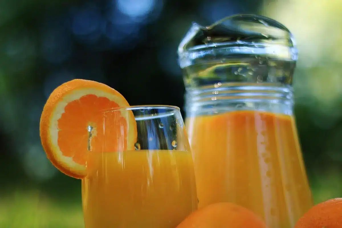 Verre de jus d'orange avec deux oranges entières à côté
