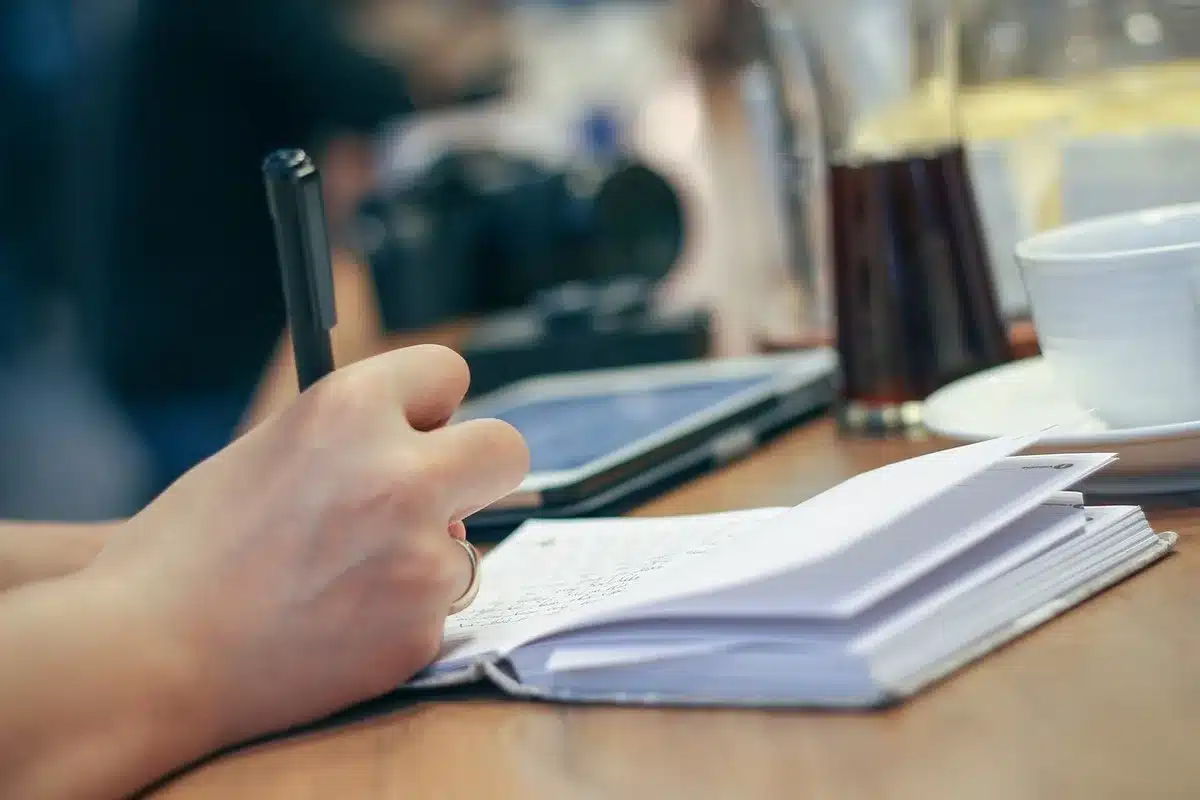 Carnet ouvert, stylo et tasse au bord d'un bureau éclairé par la lumière du jour