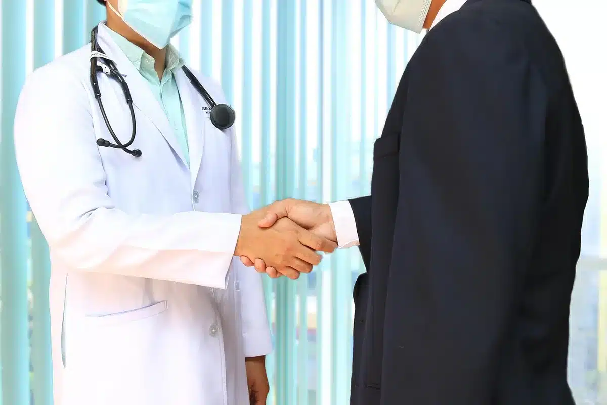 Mains sur dossier de chaise près d'une fenêtre, stéthoscope et dossiers médicaux en arrière-plan